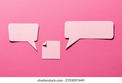 Speech bubbles and paper memo notes with folded dog-ear earmark and copy space for text on pink background, communication dialog concept top view flat lay