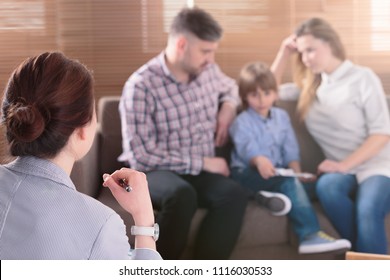 Speech therapist listening to parents talk about their son's problem in blurred background
