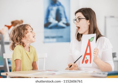 Speech Therapist Working With A Child On A Correct Pronunciation Using A Prop With A Letter 'a' Picture.