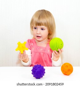 Speech Therapy, The Development Of Fine Motor Skills. The Baby Plays With Bright Balls Of Different Sizes.