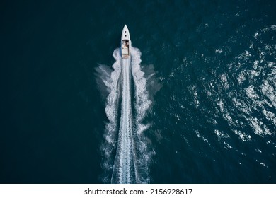 Speed boat faster movement on the water top view. Speedboat movement on the water. Large white boat driving on dark water. Speedboat wave speed water. Speedboat aerial view.