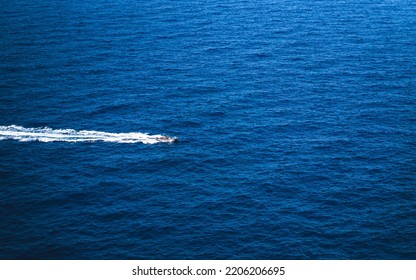 Speed Boat Racing Through The Blue Sea, Leaving A White Wake Behind It