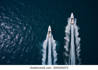 Speed Boats Movement On The Water. Speed Boats On Dark Blue Water Aerial View. Two Speed Boats Moving Fast On Dark Blue Water.. Large White Boat Driving On Dark Water.