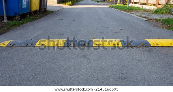 Speed bump on the\
road, yellow and black striped speed bump in asphalt road to slow\
down fast moving cars