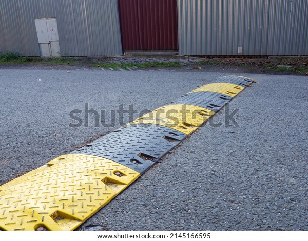 Speed bump on the\
road, yellow and black striped speed bump in asphalt road to slow\
down fast moving cars