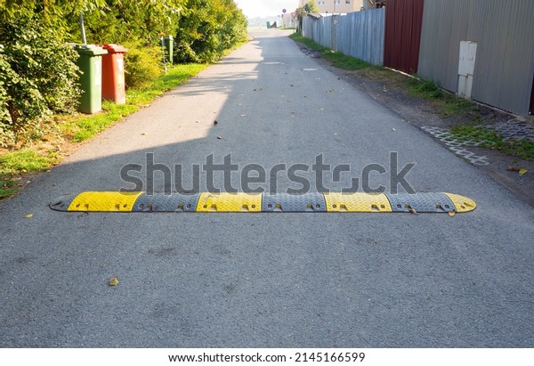 Speed bump on the
road, yellow and black striped speed bump in asphalt road to slow
down fast moving cars