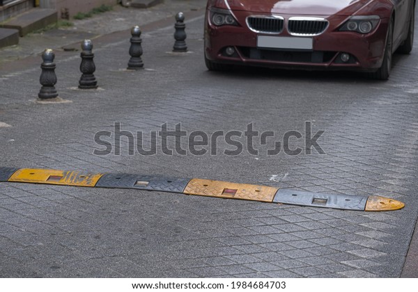 Speed\
bump on the street,  metal bollards on the\
roadside