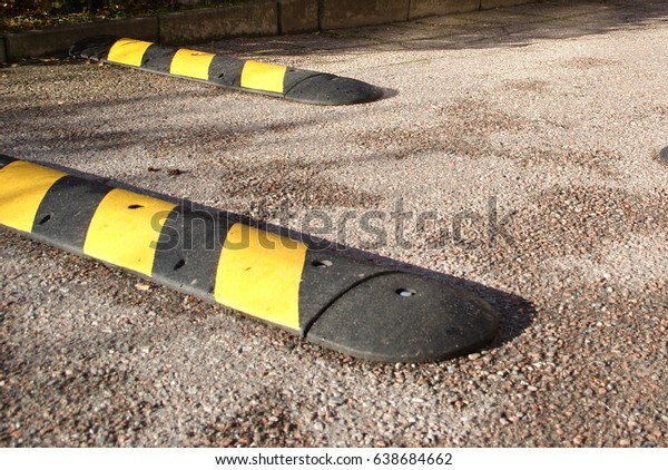 Speed bumps on a\
sunny morning. Placed on pavement to slow down speed of motorbikes,\
mopeds, cars and\
bicycles.