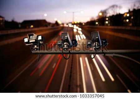 Speed camera monitoring busy traffic road at night. Highway underpass traffics present, long exposure applied lights trail present.  


