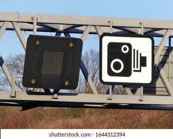 Speed Camera Sign And Variable Speed Limit Display On Gantry Above The M25 Motorway In Hertfordshire, England, UK