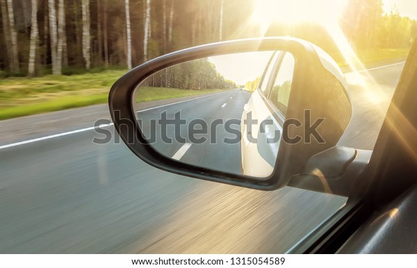 Speed car driving, view from the mirror on an empty\
highway, motion blur.