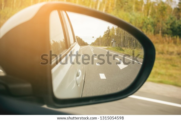 Speed car driving, view from the mirror on an\
empty highway, motion blur\
closeup.