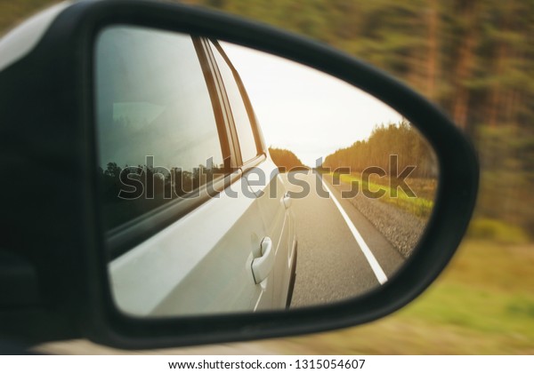 Speed car driving, view from the mirror on an\
empty highway, motion blur\
closeup.