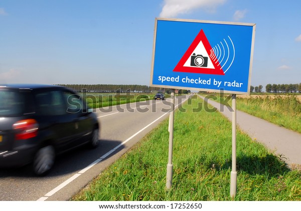 Speed checked by radar roadsign in rural\
landscape and speeding car with motion\
blur