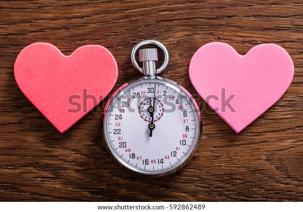 Speed Dating Concept. Two Heart Shapes And A Stop\
Watch On Wooden Desk