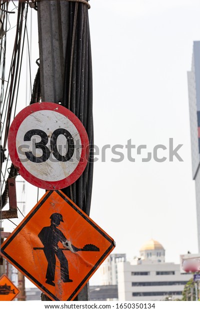 Speed limit sign with construction sign underneath,\
implying that a car can drive only 30kilometers per hour due to\
construction site ahead, showing inconvenience and danger on the\
road.