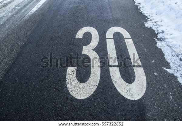 speed limit\
sign on a tarmac road with snow and\
ice