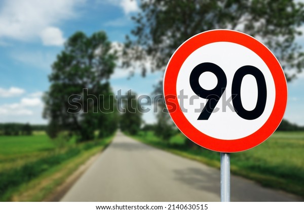 Speed limit\
sign with trees behind. Maximum ninety kilometers per hour. Safety\
on road background. White round sign red border line. Traffic\
ticket background. Speeding\
fine.