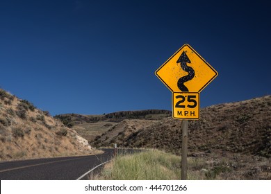 Speed limit traffic sign,25 MPH and winding road caution symbol for safety drive in the country black road,dessert mountain on the side with big blue sky with toned color and selective focus