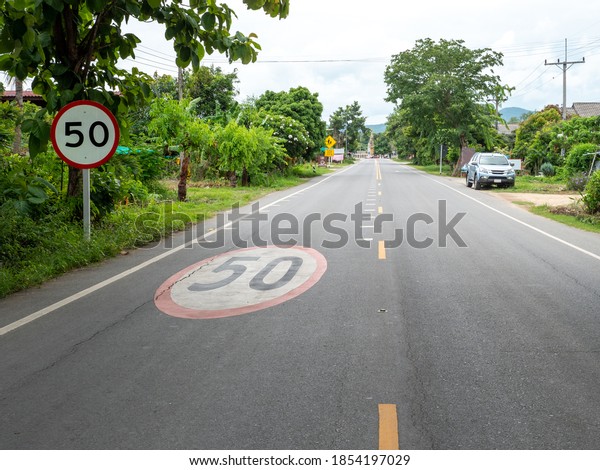 speed limit warning sign at post and\
on road surface near school and community area in countryside\
village for awareness to driver be careful the\
accident