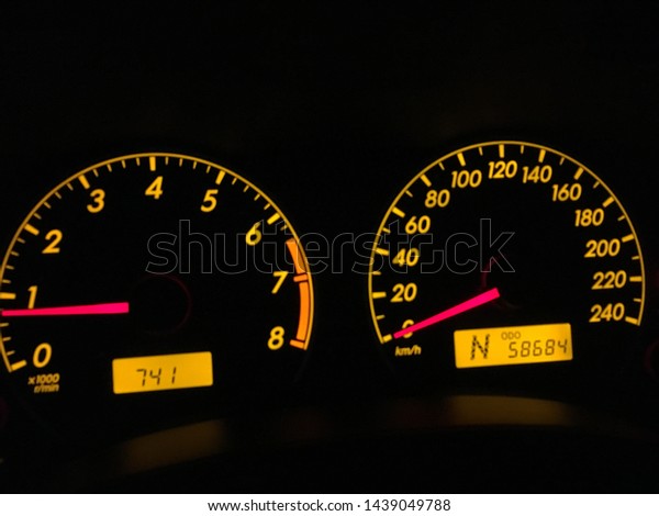Speed meter gauge with orange light\
in the night time. Speed at zero kilometer per\
hour.