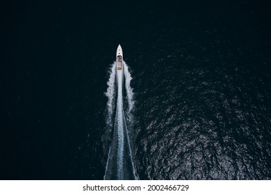 Speedboat movement on the water.Speedboat wave speed water. Large white boat driving on dark water. Speedboat on dark blue water aerial view. Speed boat faster movement top view.