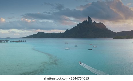 Speedboat sailing turquoise water near tropical island, green mountains and bungalows on water at sunset. Bora Bora, French Polynesia exotic paradise. Perfect summer travel vacation aerial background - Powered by Shutterstock