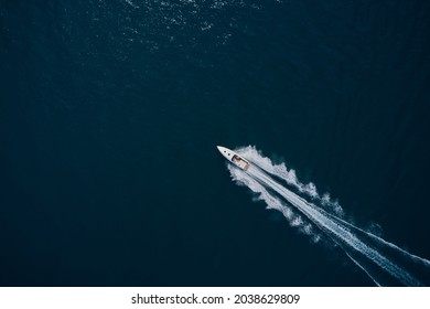 Speedboat wave speed water. Speedboat movement on the water. Large white boat driving on dark water. Speedboat on dark blue water aerial view.