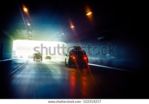 Speeding car inside a highway tunnel exiting to\
white calm light