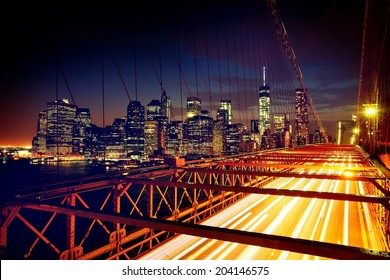 Speeding cars on Brooklyn Bridge, Downtown Manhattan, New York. Night scene. Light trails. City lights. Urban living and transportation concept