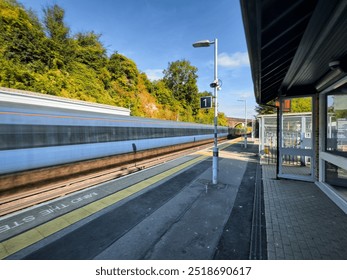 Speeding commuter train passing through station in Kent England 