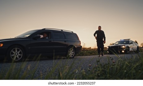 Speeding Driver Gets Pulled Over By Police Patrolling Car . Wide Shot of the Two Cars Stopped in a Road Crossing and Officer Walking Towards Suspect. Drunk Driver Gets Caught by Professional Cop