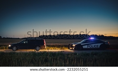 Speeding Driver Gets Pulled Over By Police Patrolling Car During Sunset. Wide Shot of the Two Cars Stopped in a Road Crossing an Open Field. Drunk Driver Gets Caught by Professional Officers