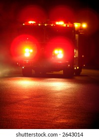 Speeding Fire Truck With Flashing Emergency Warning Lights Driving Fast To A Disaster Response Scene On A Street At Night