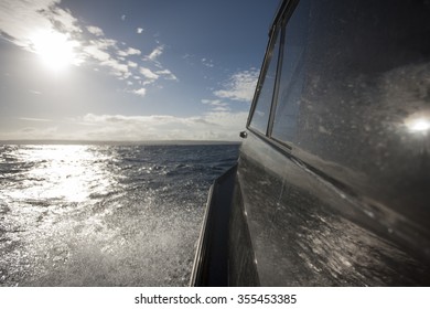 Speeding through the ocean on a black motorboat or yacht with a close up view of a window and ocean spray