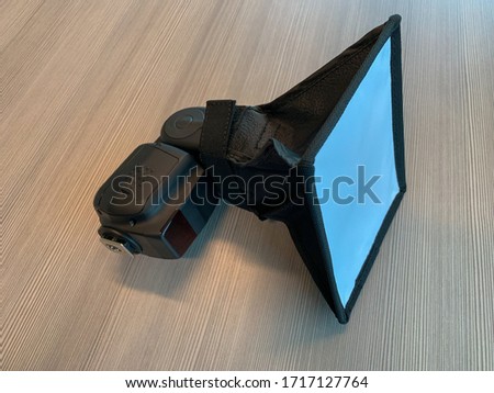 A speedlight with a mini softbox to diffuse the flash light.