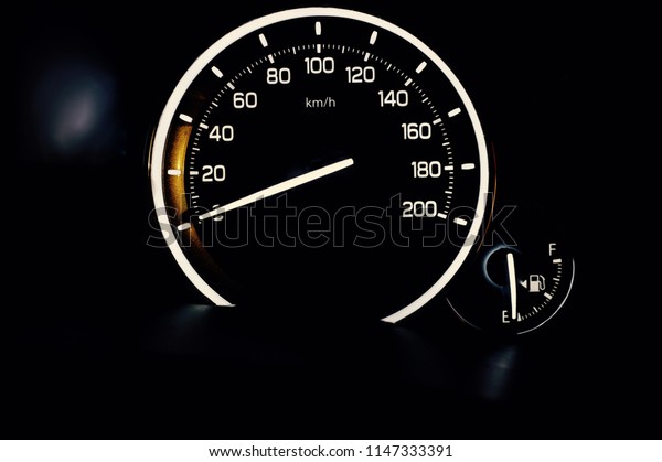 Speedometer and fuel gauge. Brightly lit\
up in white backlight. Isolated against\
black.