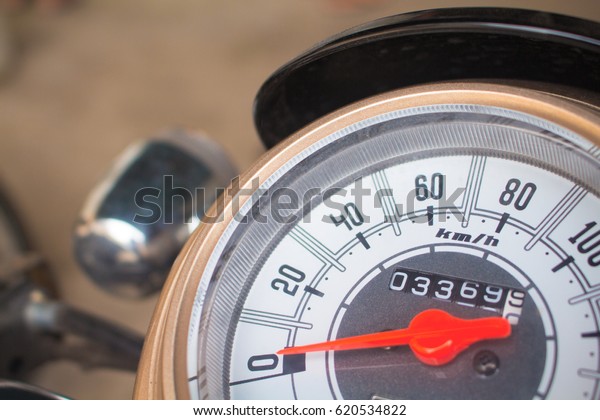 Speedometer on motorcycle dashboard. Round\
speedometer with red arrow. Speed zero shown. Full stop of\
motorbike. Transport closeup photo. Motorbike electric gear.\
Concept image for\
stagnation