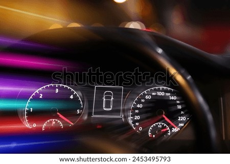 Speedometer and tachometer behind steering wheel in car, motion blur effect
