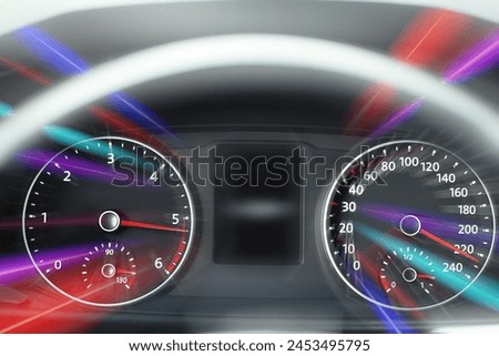 Speedometer and tachometer behind steering wheel in car, motion blur effect