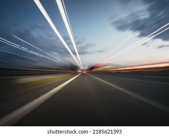 Speedy road drive along the evening highway. Front view from the car window to the road and other vehicles with beautiful light trails. - Shutterstock ID 2185621393