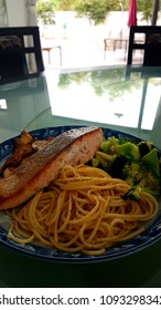 Speghetti Agolio Olio With Pan Fried Salmon, Stir Fried Broccoli And Mushrooms. Done By Private Chef. Food Placed On Wooden Table At Sun Deck 