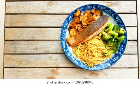 Speghetti Agolio Olio With Pan Fried Salmon, Stir Fried Broccoli And Mushrooms. Done By Private Chef. Food Placed On Wooden Table At Sun Deck 