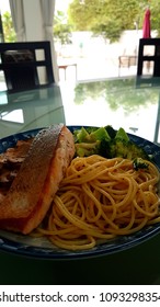 Speghetti Agolio Olio With Pan Fried Salmon, Stir Fried Broccoli And Mushrooms. Done By Private Chef. Food Placed On Wooden Table At Sun Deck 