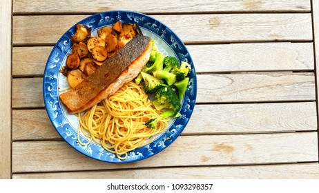 Speghetti Agolio Olio With Pan Fried Salmon, Stir Fried Broccoli And Mushrooms. Done By Private Chef. Food Placed On Wooden Table At Sun Deck 