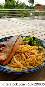 Speghetti Agolio Olio With Pan Fried Salmon, Stir Fried Broccoli And Mushrooms. Done By Private Chef. Food Placed On Wooden Table At Sun Deck 