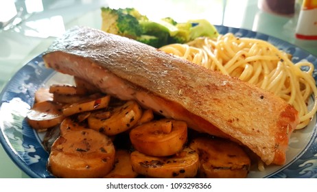 Speghetti Agolio Olio With Pan Fried Salmon, Stir Fried Broccoli And Mushrooms. Done By Private Chef. Food Placed On Wooden Table At Sun Deck 