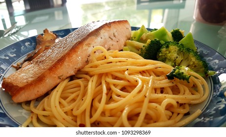 Speghetti Agolio Olio With Pan Fried Salmon, Stir Fried Broccoli And Mushrooms. Done By Private Chef. Food Placed On Wooden Table At Sun Deck 