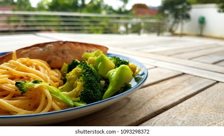 Speghetti Agolio Olio With Pan Fried Salmon, Stir Fried Broccoli And Mushrooms. Done By Private Chef. Food Placed On Wooden Table At Sun Deck 