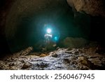 A speleologist explores an underground cave, a geologist studies a hole in the rock of the mountain